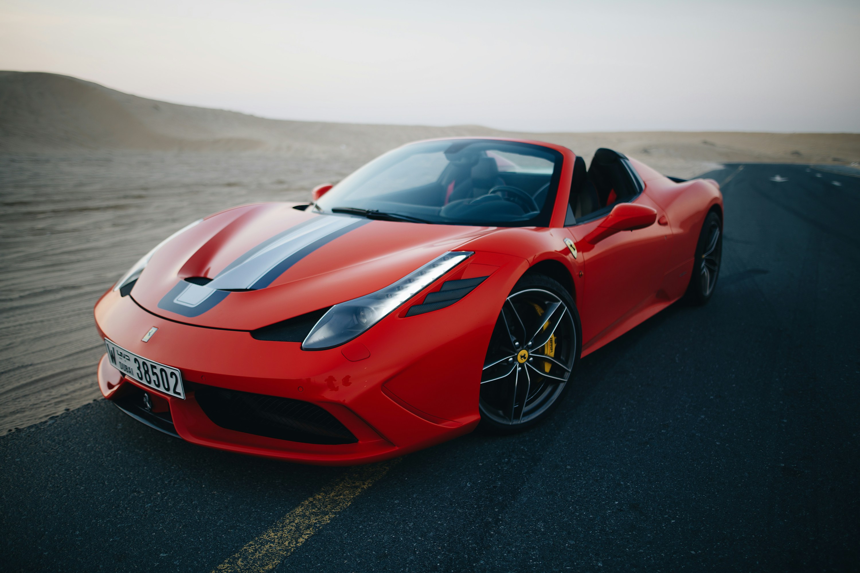 A red Ferrari on an open road in the soft desert light
